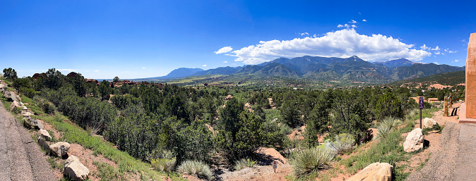 An expansive panorama captures the Valley of the Gods Park in Colorado Springs, Colorado, with the towering Pikes Peak dominating the backdrop of the surrounding mountain range.