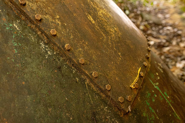 Heavily rusted industrial tanks stand abandoned in a natural setting. These images highlight the beautiful decay and intricate textures of corrosion as nature begins to reclaim these forgotten relics