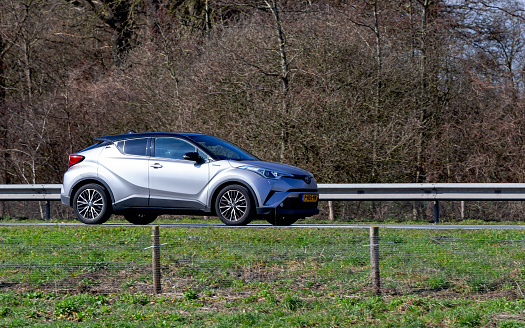 Netherlands, Overijssel, Twente, Wierden, March 19th 2023, side/front view close-up of a Dutch gray 2018 hybrid Toyota 1st generation C-HR hatchback driving on the N36 at Wierden, the C-HR is made by Japanese car manufacturer Toyota Motor Corporation since 2016, the N36 is a 36 kilometer long highway from Wierden to Ommen