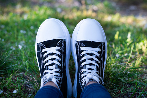 Sneakers in crisp black and white hues blend seamlessly with the serene, sunny park ambiance.