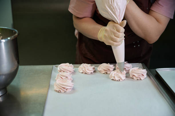 istock Confectioner piping out berry mixture from pastry bag into baking sheet 2149887097