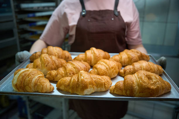 istock Female holding baking sheet with freshly baked buttery croissants 2149887128
