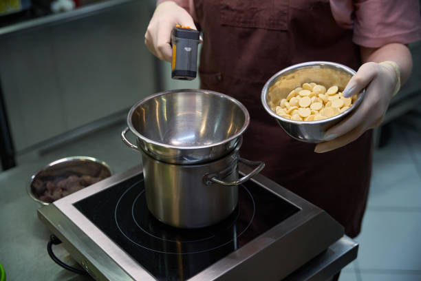 istock Confectioner using kitchen thermometer to melt white chocolate chips on steam bath 2149888965