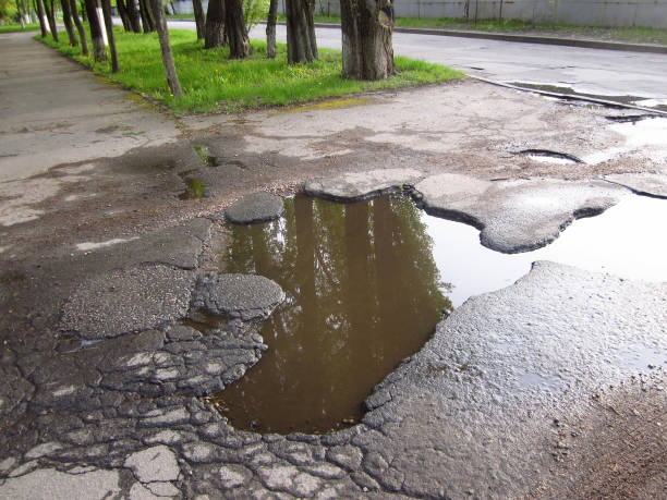 istock Old sidewalk pavement big asphalt pothole, broken asphalt road puddle. 2149890269