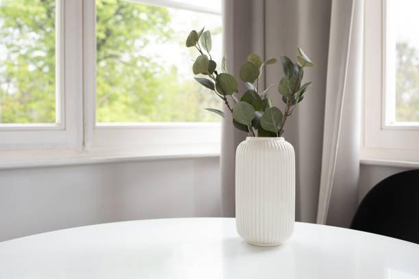 istock Background of white vase with artificial eucalyptus on white table and window at the back 2149892124