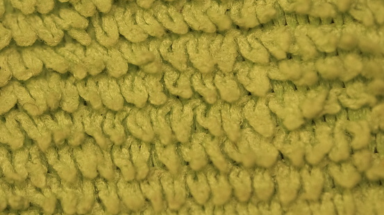 In this macro shot, the green wool sweater is closely examined in detail. The texture of the wool fibers and the pattern of the fabric take center stage in the image, defining the softness and texture of the sweater