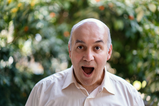 Mid adult bald man looking at camera with a surprised face expression