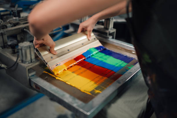 istock Close up of graphic worker's hands using squeegee for screen printing. 2149896625