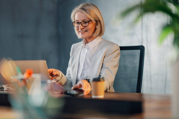 Senior businesswoman sitting at office and using cutting edge technologies