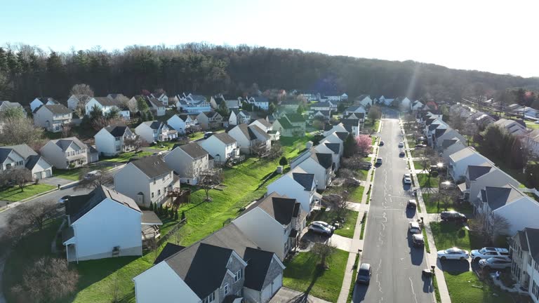 Similar new homes in idyllic suburb district of America at sunset. Springtime in suburbia of American City. Establishing drone shot.