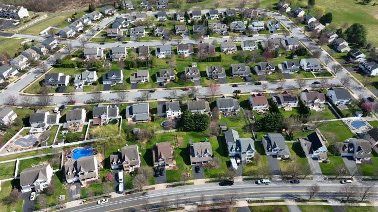 Luxury Neighborhood in America with swimming pool at sunlight. Springtime in suburb district of town in USA. Upper Class single family houses. Aerial rising top down shot.
