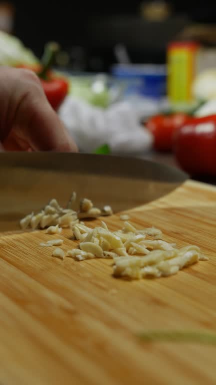 Men's hands are chopping a clove of garlic.