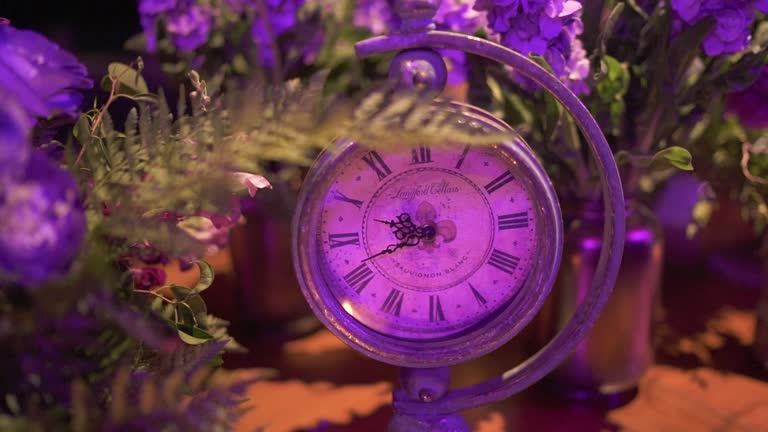 Old rusty clock in event floral decoration. Fantasy concept. Close up. Slow motion 100 fps