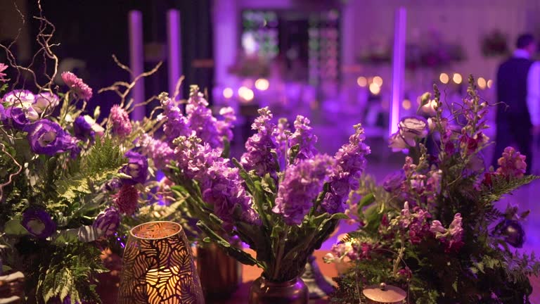Colorful purple floral decoration with candle lamps on event table. Slow motion 100 fps