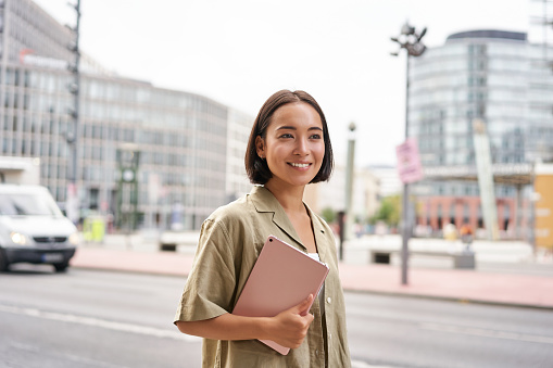 Portrait of young stylish woman walking with tablet, going somewhere in city photo