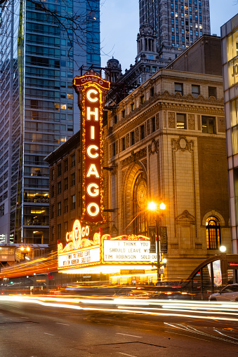 At dusk the landmark Chicago Theater is illuminated with cars driving past in a streak of motion blur with a long exposure.