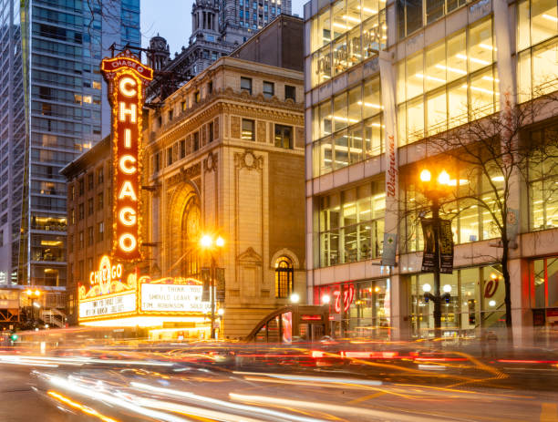 At dusk the landmark Chicago Theater is illuminated with cars driving past in a streak of motion blur with a long exposure.