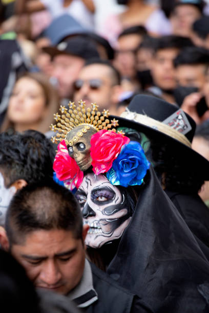 29th Oct, 2022, Mexico City, Mexico State, Mexico. A young woman with elaborate face painting and head dress at a huge annual Day of the Dead parade that takes place in Mexico City at the end of every October. The Day of the Dead is celebrated all over Mexico at the end of October with paredes, fiestas and families observing and revering their deceased  loved ones at their graves.