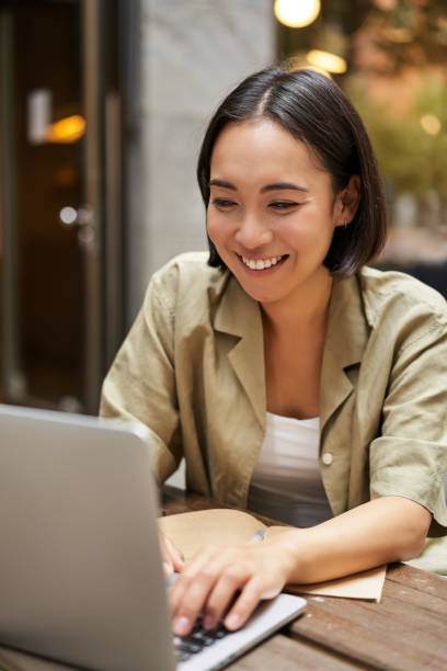 istock Smiling young woman working from cafe or co-working space, sitting with laptop, studying or doing homework, looking happy 2149908792