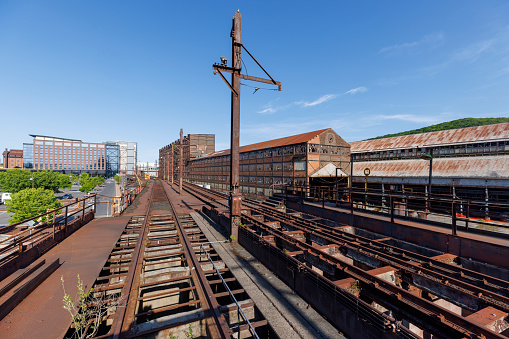 Historic Steelstacks — an abandoned steel plant in Bethlehem, Pennsylvania. The aged structures and rusted railway tracks under a clear blue sky. The industrial landscape symbolizes the decline of traditional manufacturing in America and serves as a reminder of the region's industrial past.