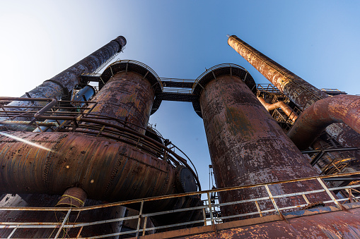 The towering furnaces of an abandoned steel plant in Bethlehem, Pennsylvania. Rusted giants stand as monuments of the industrial age, set against a clear blue sky. Low angle view