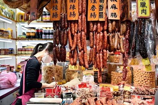 Nanmen market (Publicly accessible), TW-01.18.24: Liver sausage and Chinese sausage: Lunar New Year staples in Chinese-speaking areas, made beforehand and savored during celebrations. They're made by marinating, drying, or smoking meat. A vendor is tending to their store and waiting for customers to come in.