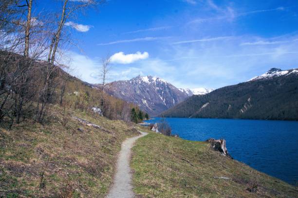 istock Narrow footpath winding next to large calm lake 2149911479