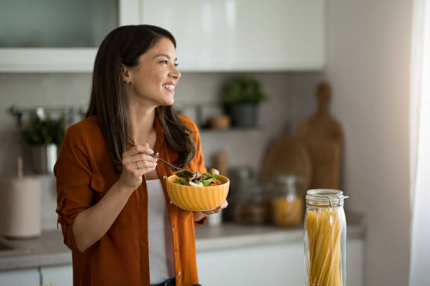 Woman eating a salad in the kitchen.