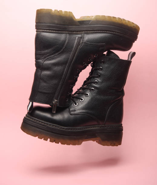 Black leather boots floating on pink background