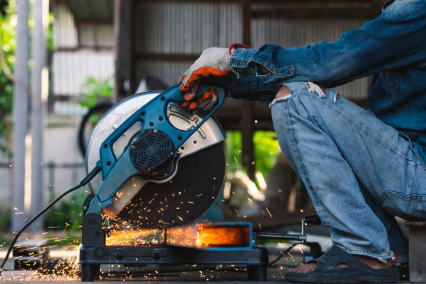 Worker cutting metal steel pipe using mechanic round saw with sparkling light