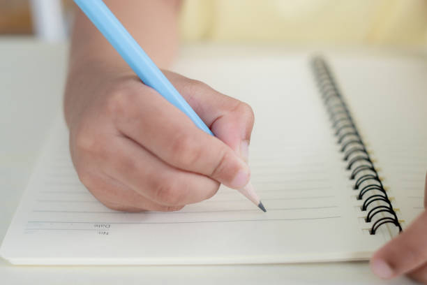 istock Close up to a child hand writing on a notebook using blue pencil, blank paper 2149916977