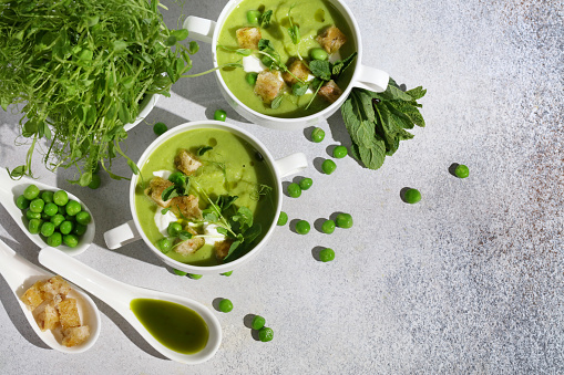 Refreshing Summer Pea Soup with Crispy Croutons, Sour Cream, Fragrant Mint, Pea Shoots, and Vibrant Parsley Oil. Plant-Based Food Inspiration. Handcrafted Image, Not AI