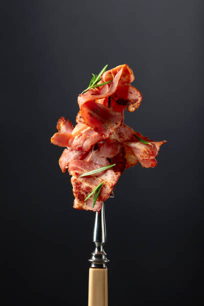 istock Roasted bacon slices with rosemary on a fork. 2149921740