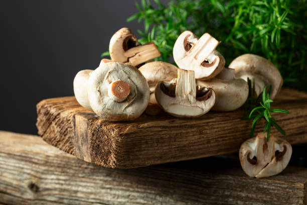 istock White champignons with rosemary on a wooden board. 2149921766