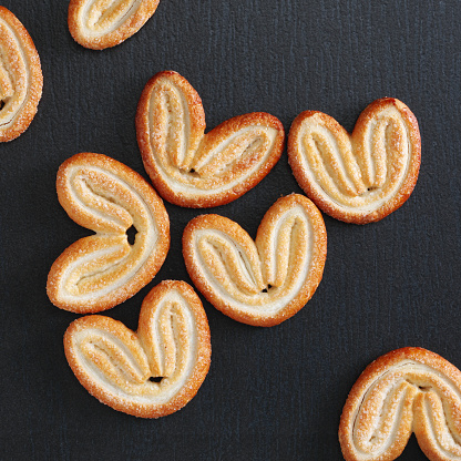 Palmier, also elephant ears cookies on black stone background, top view