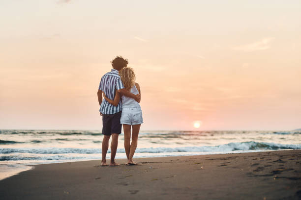 istock Back view of embraced couple on the beach at sunset. 2149924103