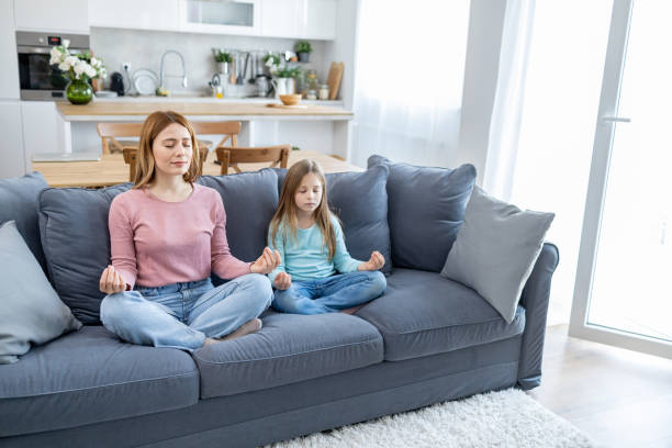 istock Mother and daughter meditating on couch quietly 2149924245