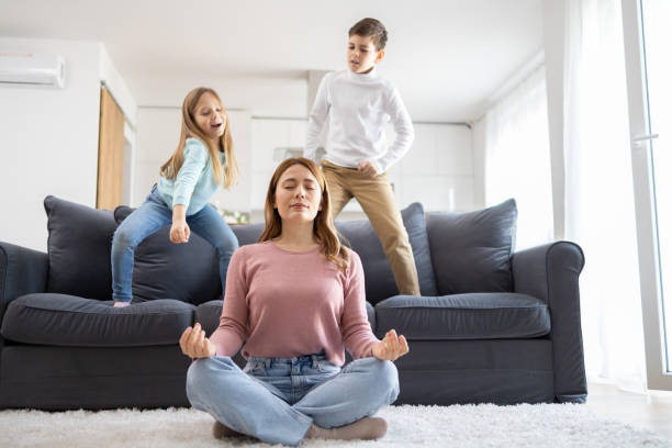 istock Mother meditating with playful children behind 2149924255