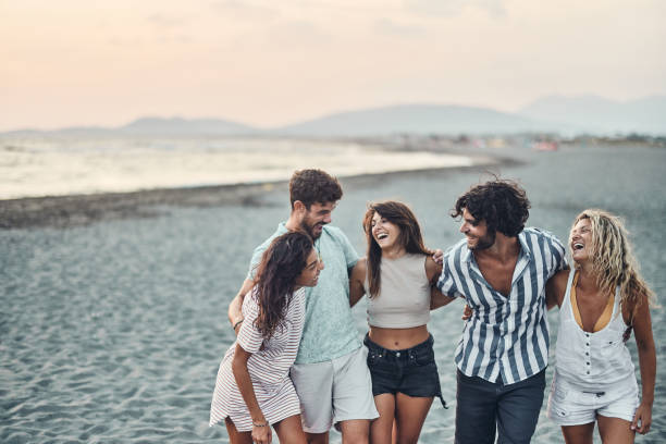 istock Young happy friends talking while walking embraced on the beach. 2149924918