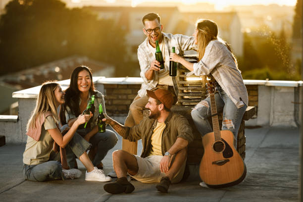 istock Cheerful friends toasting with beer on a rooftop at sunset. 2149925204