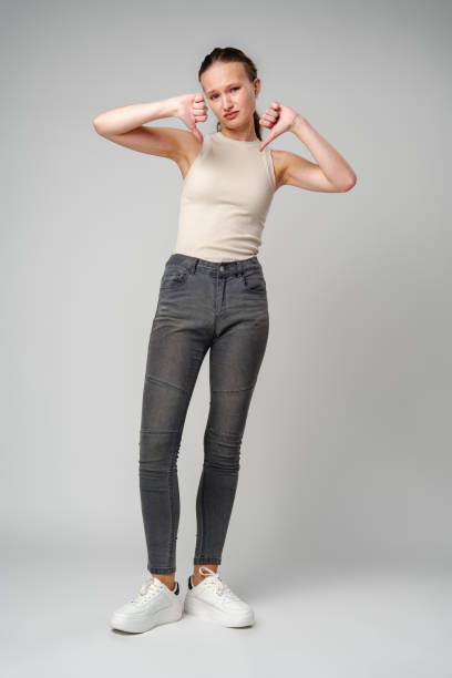 istock Young Woman Giving Thumbs Down Gesture Against a Neutral Background. 2149927446