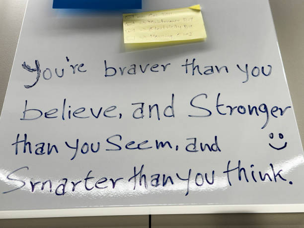 istock Close-up image of rectangular, yellow sticky note stuck on whiteboard, check list of bills needing to be paid, checkboxes with and without check marks, motivational quote written in non-permanent ink marker, focus on foreground 2149928162