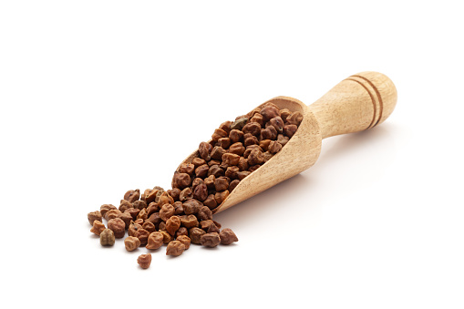 Front view of a wooden scoop filled with Organic Black Chickpeas (Cicer arietinum) or Kala Chana. Isolated on a white background.