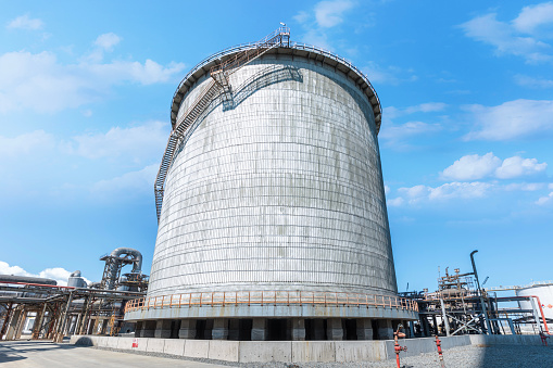 Double wall, cylindrical and vertical ammoniac storage tank in the factory. Ammonia is used in numerous different industrial application requiring carbon storage vessels.