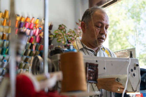 istock 50 year old Latin man sewing with sewing machine in his sewing workshop 2149929979