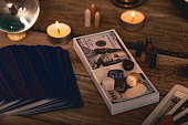 A tarot spread with The Fool card, hundred-dollar bills, and various crystals on a rustic wooden background with candles.