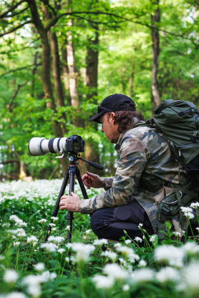 istock Man with camera on tripod photographing nature in forest 2149934312
