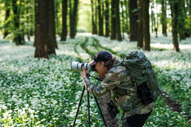 istock Man with camera on tripod photographing nature in flowering spring  forest 2149934322