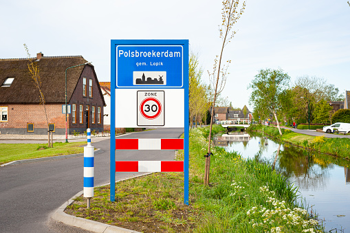 Location sign of the small village of Polsbroekerdam, municipality of Lopik in the western part of The Netherlands. Under the sign is indicated that it is a zone with a speed limit of 30.