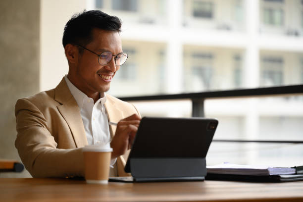 istock Smiling male entrepreneur in eyeglasses using digital tablet on an office building patio 2149935298